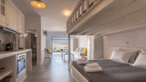 A compact hotel room with a bed, a kitchenette, and a view through an open door. - FANI DREAM SUITE By Vilos Suites (Milos)