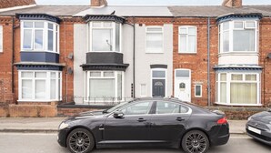 A black car parked in front of a row of terraced houses with bay windows and a front door. - Host & Stay | Clifton Studio 1 (Darlington)
