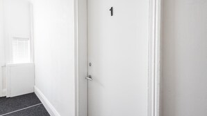 A white door with a number 1 sign, a door handle, and a small window with blinds. - Host & Stay | Clifton Studio 1 (Darlington)