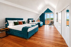 Ein modernes Hotelzimmer mit einem großen Bett, einem kleineren Bett und einer Sitzecke mit Blick.