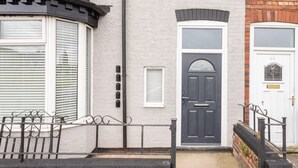 A residential building with a black front door, white-framed windows, and a small window above the door. - Host & Stay | Clifton Studio 4 (Darlington)