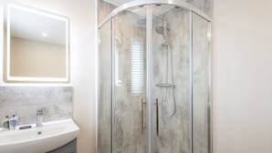 A modern bathroom with a glass-enclosed shower, a white sink with a marble countertop, and a mirror above the sink. - Host & Stay | Clifton Studio 4 (Darlington)