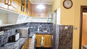 Eine Küche mit Marmorarbeitsplatten, Holzschränken, einem eingebauten Backofen, einem Kühlschrank und einer Wanduhr.