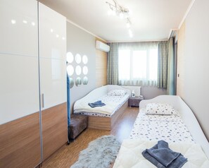 A modern bedroom with two beds, a wardrobe, a mirror wall, and a window with curtains. - Premium Lazur - Sea garden Burgas - TOP Location  (Burgas)
