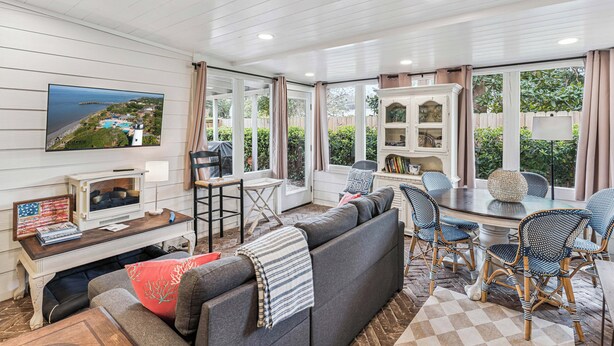 A cozy living room with a large TV, comfortable seating, and a view of the outdoors.