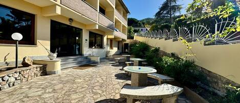 A courtyard with stone flooring, outdoor seating, and a building with multiple balconies.