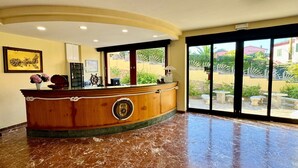 A reception area with a wooden counter, a ship's wheel, and a clock on the wall. - Hotel Fontalleccio (Marciana)