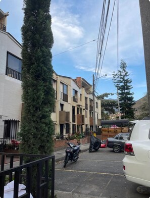 Stroll through a charming residential street lined with apartment buildings and lush trees.