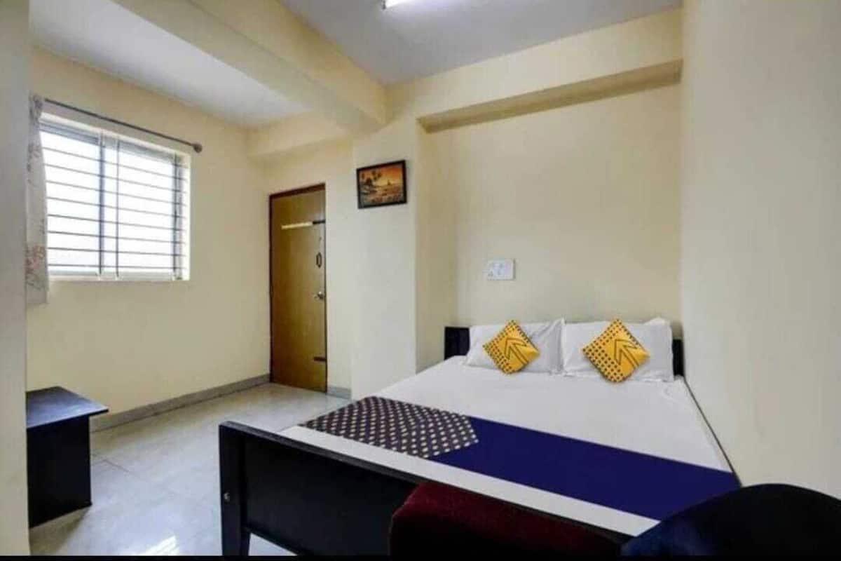 A bedroom with a bed, a window, a door, and a small table.