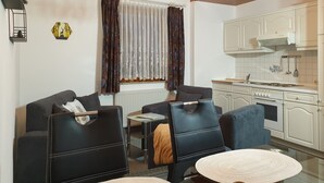 A modern kitchen with white cabinets and a built-in stove. There is a dining area with two chairs and a small table. - Gästehaus mit Fewos, Apartments und Zimmern im Thüringer Wald - Familientreffen! (Siegmundsburg)