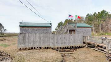A wooden structure with a green roof, a flagpole with an American flag, and a flagpole with a flag that appears to be the Italian flag.