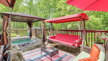 An outdoor deck with a hot tub, a swing, and a covered seating area.