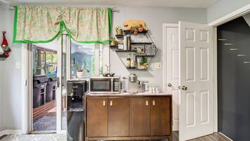 A kitchen with a microwave, coffee maker, and a cabinet with shelves.