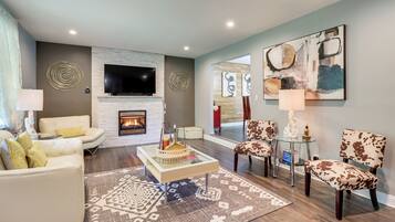 A modern living room with a fireplace, comfortable seating, and contemporary artwork.