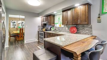 A modern kitchen with dark wood cabinets, a granite countertop, and stainless steel appliances.