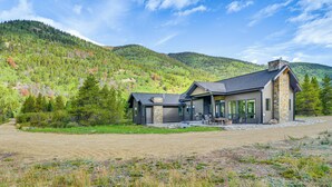 Une maison moderne avec une façade en pierre, de grandes fenêtres et un espace patio.