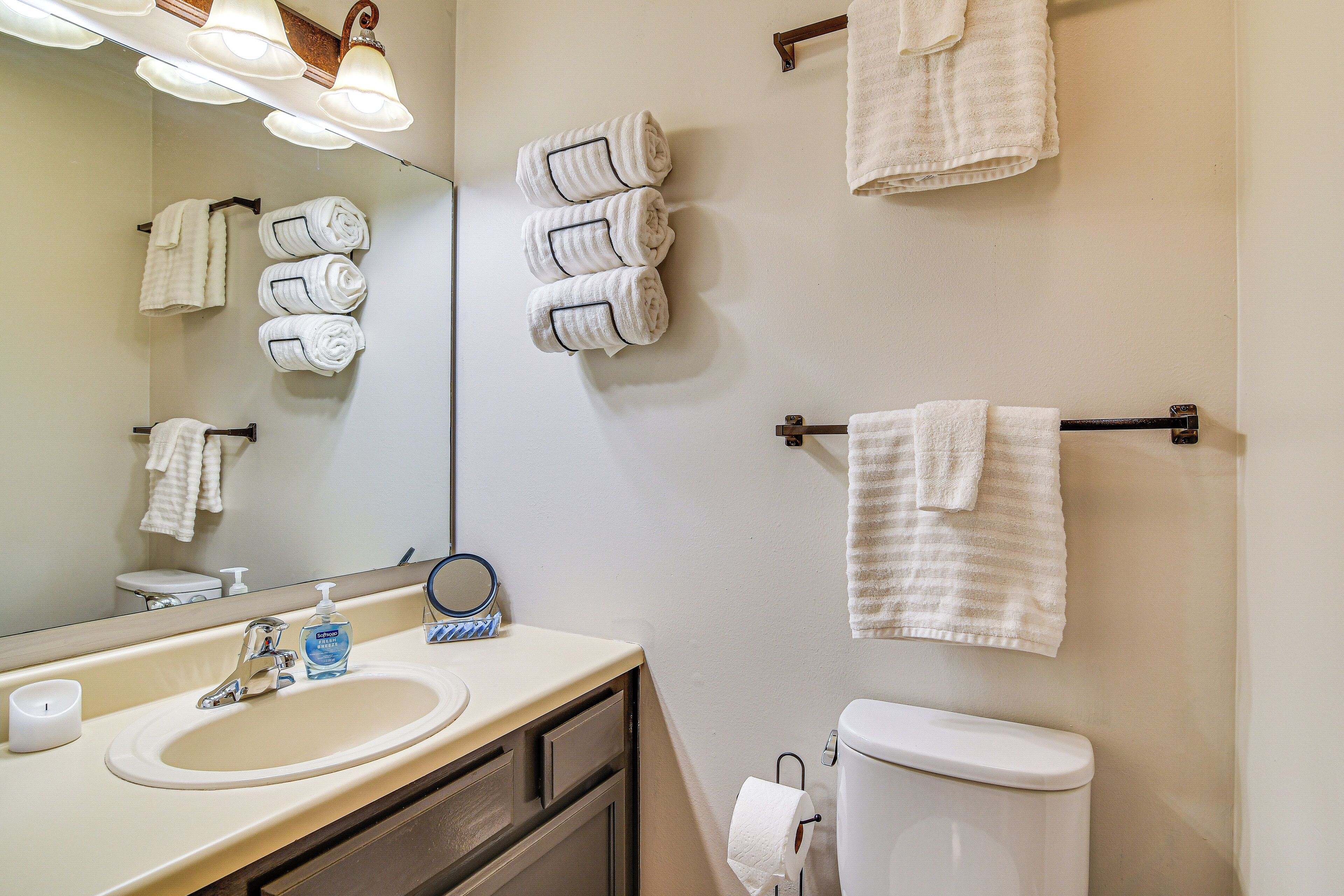 A bathroom with a sink, mirror, and multiple towels hanging on the wall.