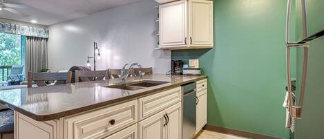 A kitchen with a large island, a dishwasher, and a refrigerator.