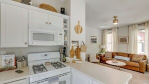 A modern kitchen with white appliances, a dining area with a round table, and a living room with a brown sofa. - Summer Village Family Cottage w/ Community Perks! (Westford)
