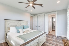 A bedroom with a wooden bed, white walls, and a ceiling fan. - Galveston Getaway w/ Outdoor Bar: Walk to Beach! (Galveston)