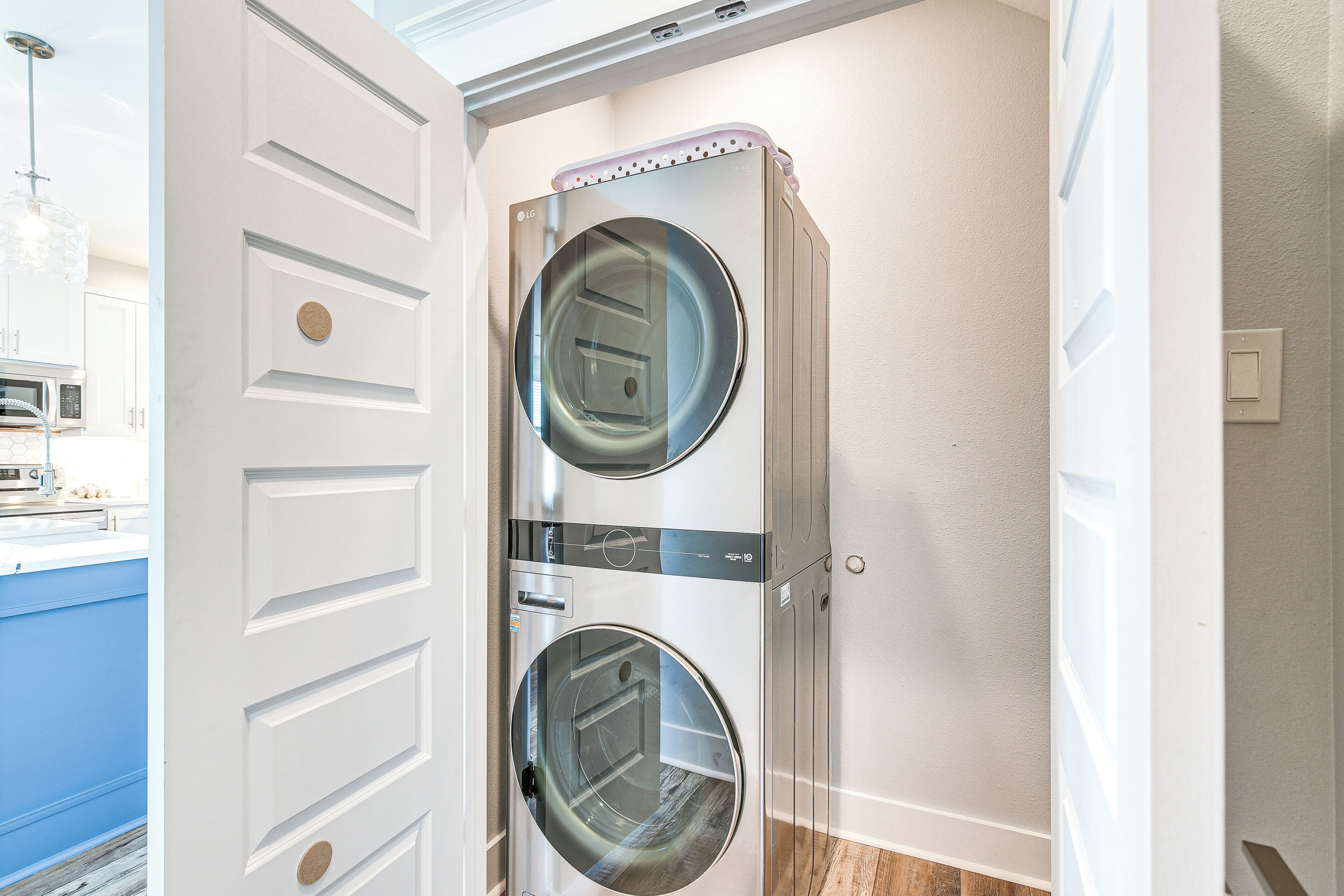 A laundry room with two front-loading washing machines, a microwave, and a blue countertop.