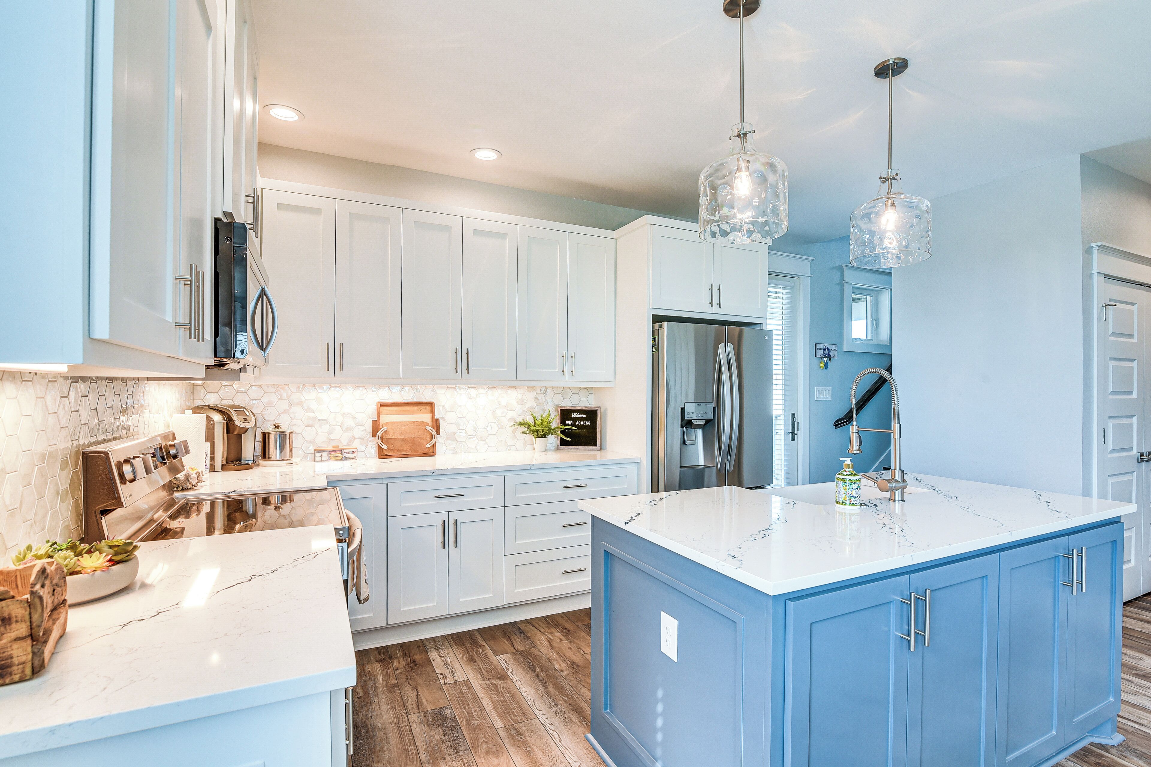 A modern kitchen with a central island, stainless steel appliances, and a backsplash with hexagonal tiles.