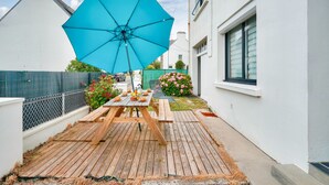 Une terrasse en bois avec une table de pique-nique et un parasol bleu.