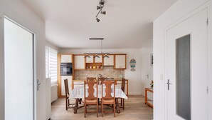Une cuisine moderne avec des meubles en bois, une table à manger avec des chaises et un luminaire suspendu.