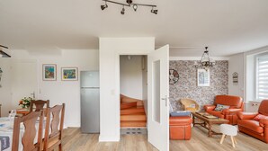 Un appartement moderne comprenant une cuisine, un coin repas et un salon. Un escalier mène à l’étage supérieur.