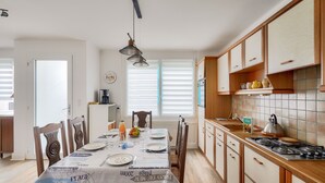 Une cuisine moderne avec des meubles en bois, une table à manger pour quatre personnes et une cuisinière à gaz.
