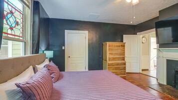 A bedroom with a bed, a dresser, a clock, and a fireplace.
