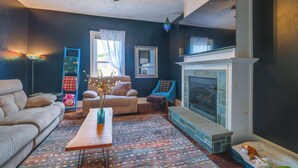 A living room with a fireplace, a sofa, a coffee table, and a blue armchair. - Walk to U of Lynchburg: Big Home w/ Yard & Hot Tub (Lynchburg)