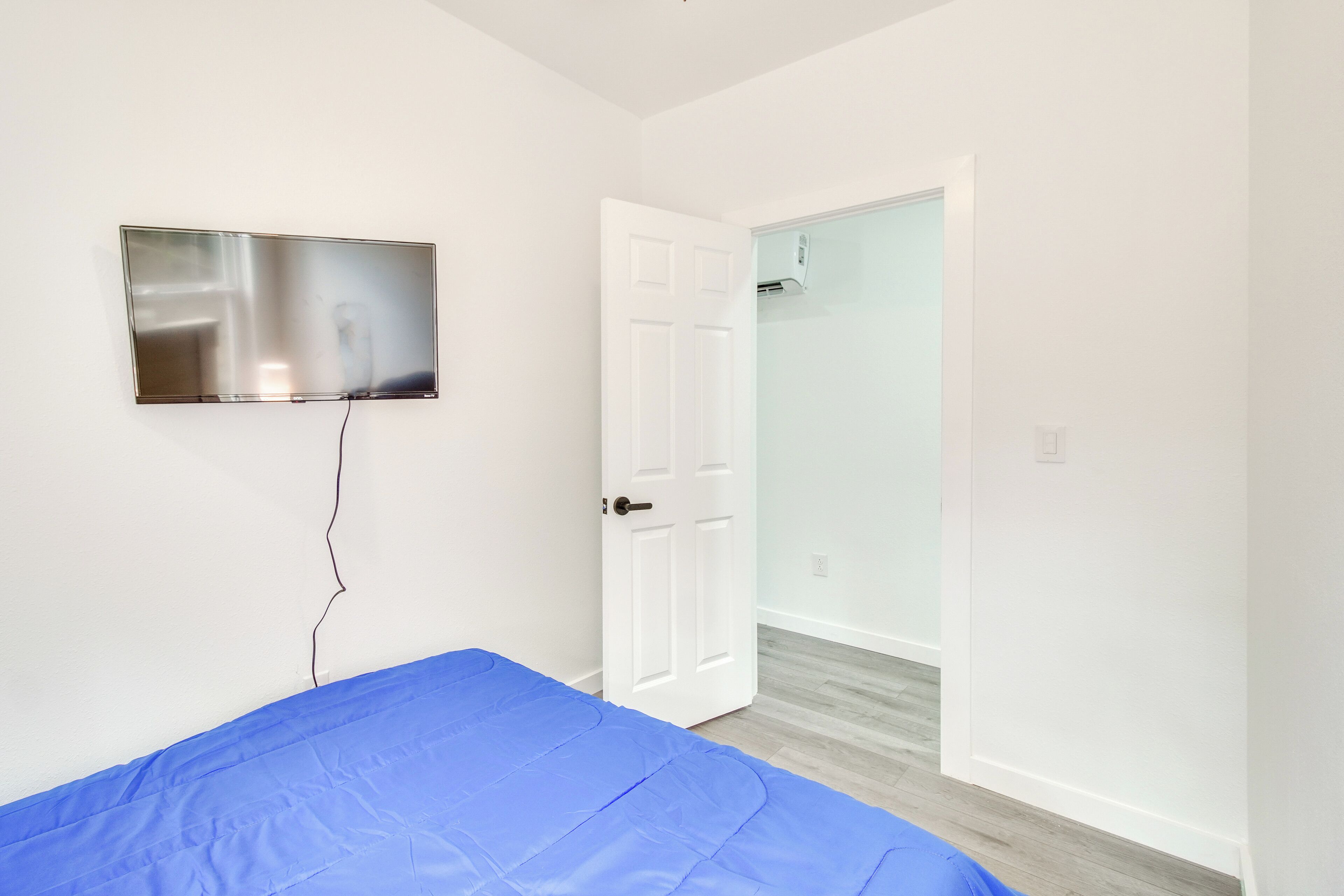 Une chambre avec un lit, un téléviseur fixé au mur et une porte donnant accès à une salle de bain.