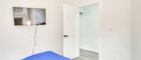 A room with a bed, a television mounted on the wall, and a door leading to a bathroom.