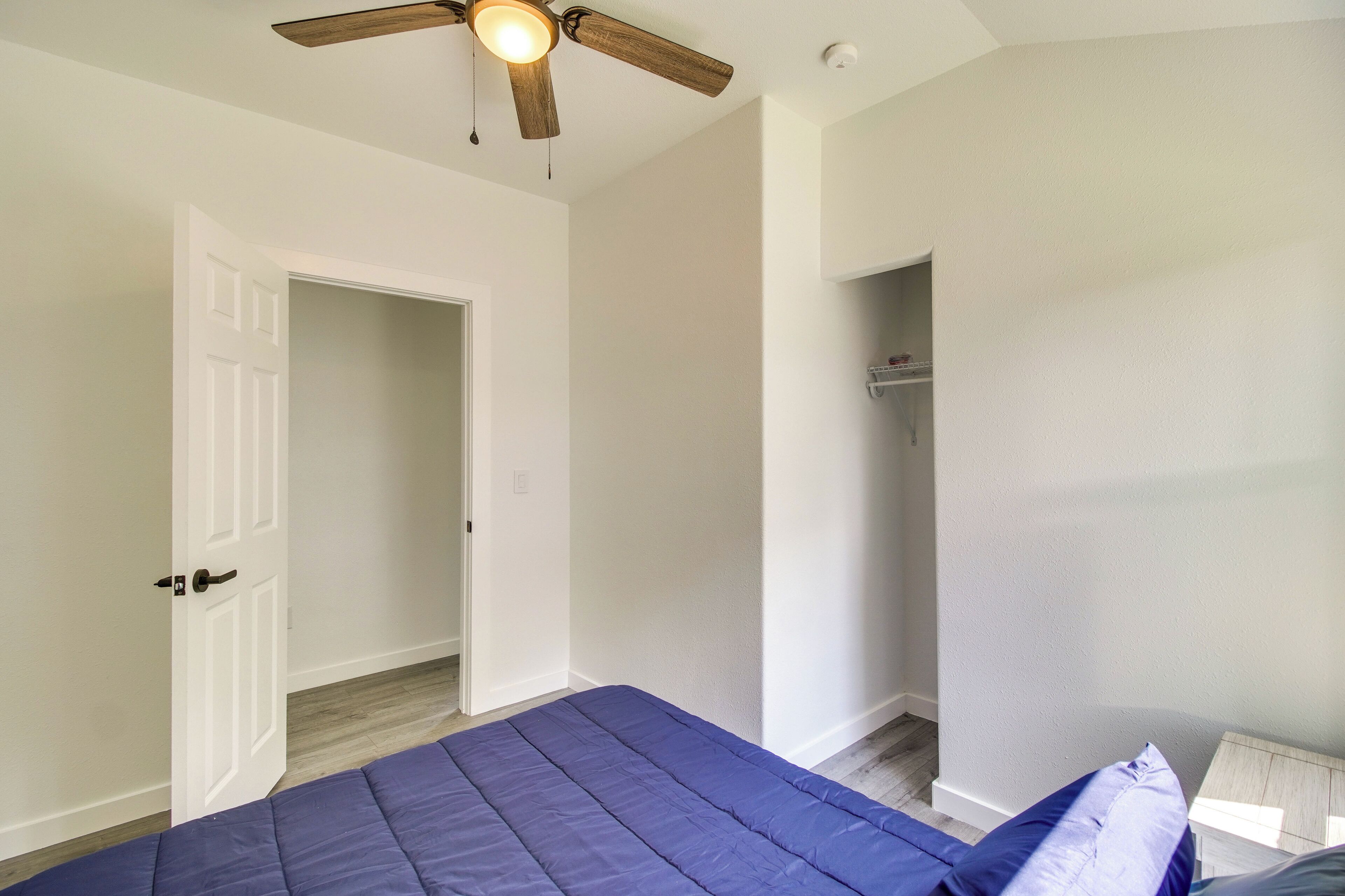 A bedroom with a bed, a ceiling fan, a white door, and a closet.