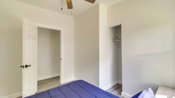 A bedroom with a bed, a ceiling fan, a white door, and a closet.