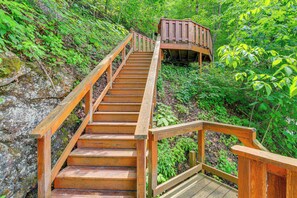 A wooden staircase leading up to a wooden platform in a lush, green forest.