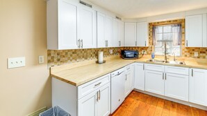 A kitchen with white cabinets, a wooden countertop, a microwave, and a window with curtains. - Peaceful South Holston Lake Cabin w/ Dock & Deck! (Abingdon)