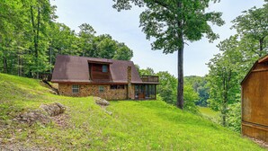 A stone house with a wooden deck, surrounded by lush greenery and trees. - Peaceful South Holston Lake Cabin w/ Dock & Deck! (Abingdon)