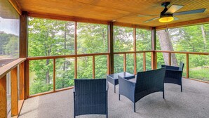 A covered outdoor area with a ceiling fan, large windows, and wicker furniture. - Peaceful South Holston Lake Cabin w/ Dock & Deck! (Abingdon)