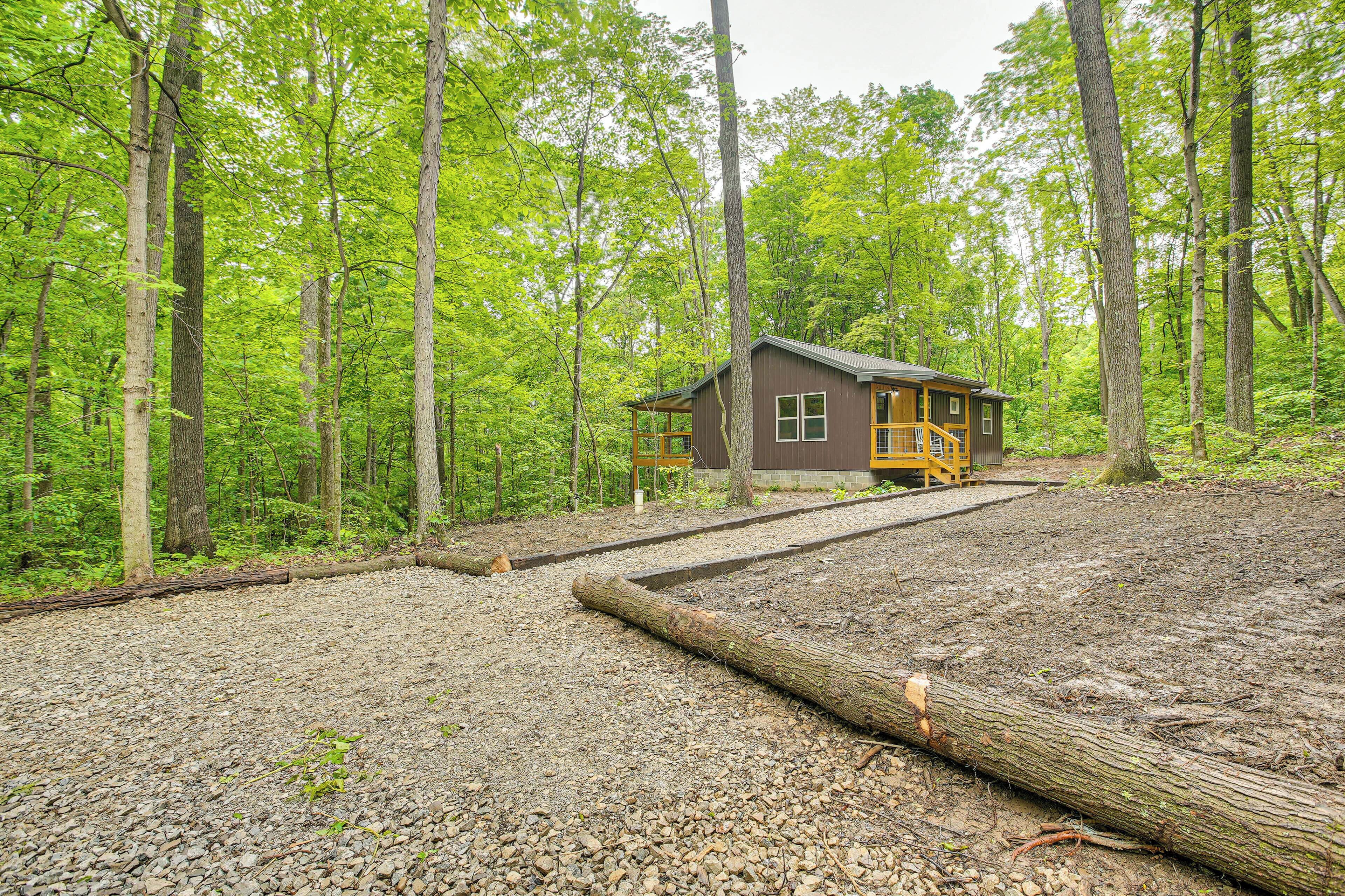 Une cabane au milieu d’une forêt, avec un chemin de gravier menant à celle-ci.