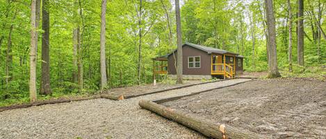 Une cabane au milieu d’une forêt, avec un chemin de gravier menant à celle-ci.