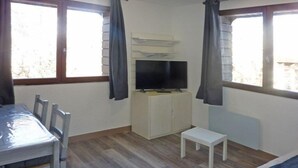 A small room with a bed, a TV on a cabinet, a table with chairs, and a window with curtains. - 3rd floor, balcony, 40m², Les Orres (Les Orres)