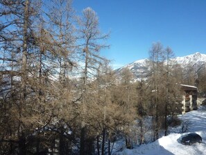 A snow-covered landscape with a mountain in the background, a building with a sloped roof, and a car parked nearby. - 50m from ski slopes, 3rd floor, balcony, 40m², Les Orres (Les Orres)