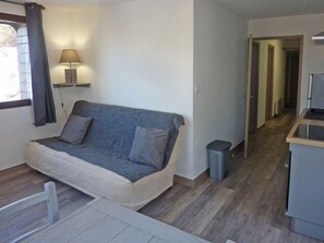 A compact living space with a sofa, a lamp, a trash bin, and a kitchenette area. - 50m from ski slopes, 3rd floor, balcony, 40m², Les Orres (Les Orres)