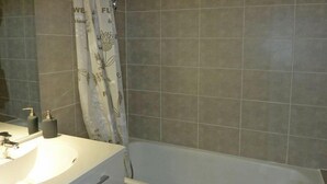 A bathroom with a white sink, a shower curtain with floral patterns, and grey tiled walls. - 3rd floor, balcony, 40m², Les Orres (Les Orres)