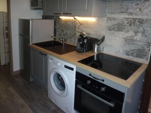 A compact kitchen with a washing machine, a microwave, a coffee maker, and a stove. - 50m from ski slopes, 3rd floor, balcony, 40m², Les Orres (Les Orres)