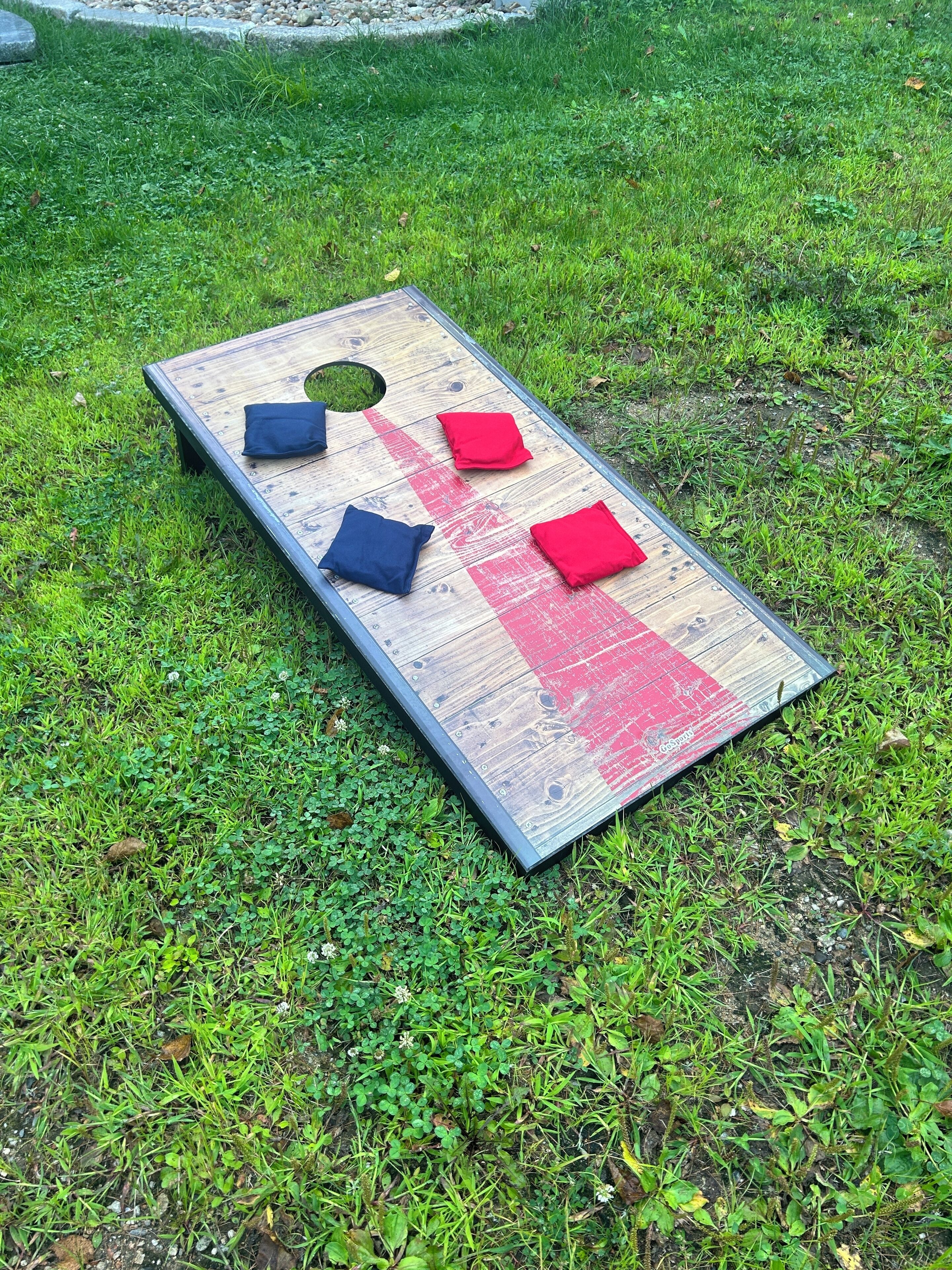 A wooden board game with four colored squares on a grassy field.