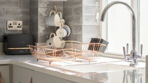 Une cuisine moderne avec des meubles gris, un évier en acier inoxydable et un égouttoir à vaisselle.