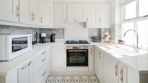 Une cuisine compacte avec des meubles blancs, un four encastré, un four à micro-ondes et un évier.